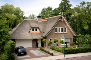 oprit en looppad voorzien van sierbestrating voor deze vrijstaande woning welke overgaat in een strakke border in de voortuin als afscheiding in deze landelijke bosrijke omgeving